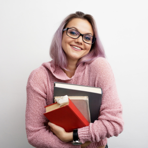 Young female adult with purple hair and glasses holding textbooks.