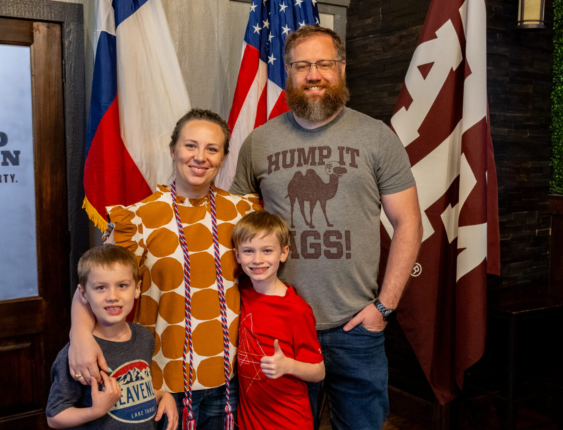 family photo in front of American, Texas, and A&M flags.