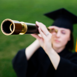 Graduate in cap and gown, looking through a telescope